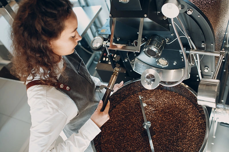 woman at coffee roaster machine