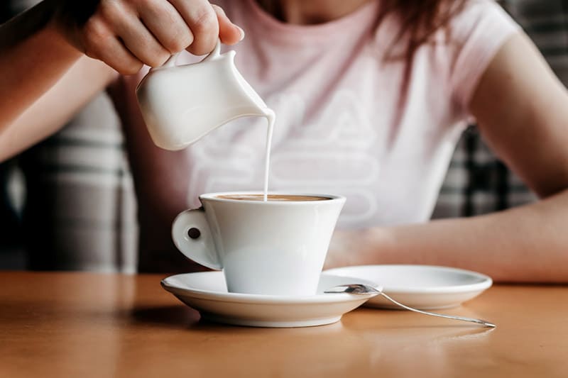 pouring cream into coffee