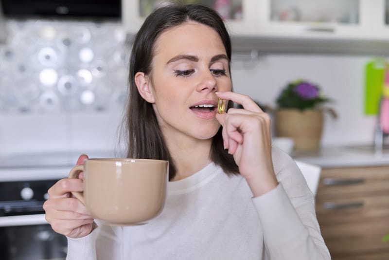 woman taking pill with coffee